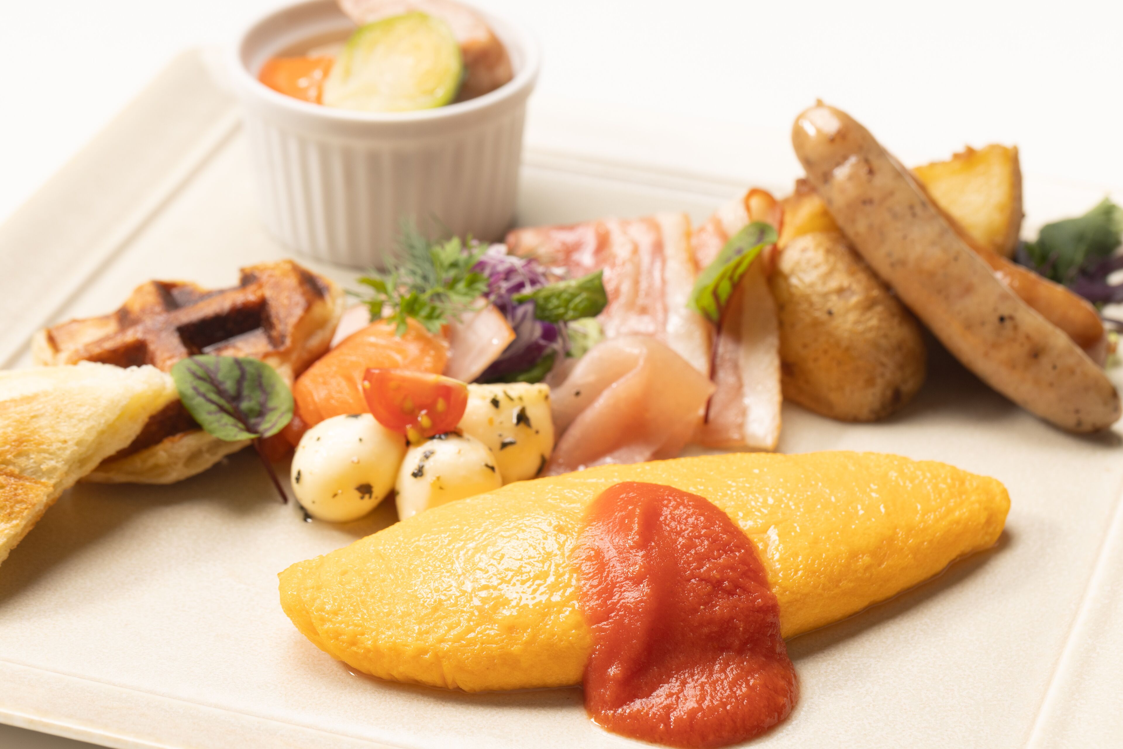 A plate of food with grilled meat, potatoes, and a slice of yellow fruit with red sauce.
