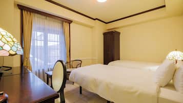 A hotel room with a bed, a desk, a chair, and a cabinet.