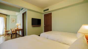 A hotel room with two beds, a desk with a chair, a television on the wall, and a door.