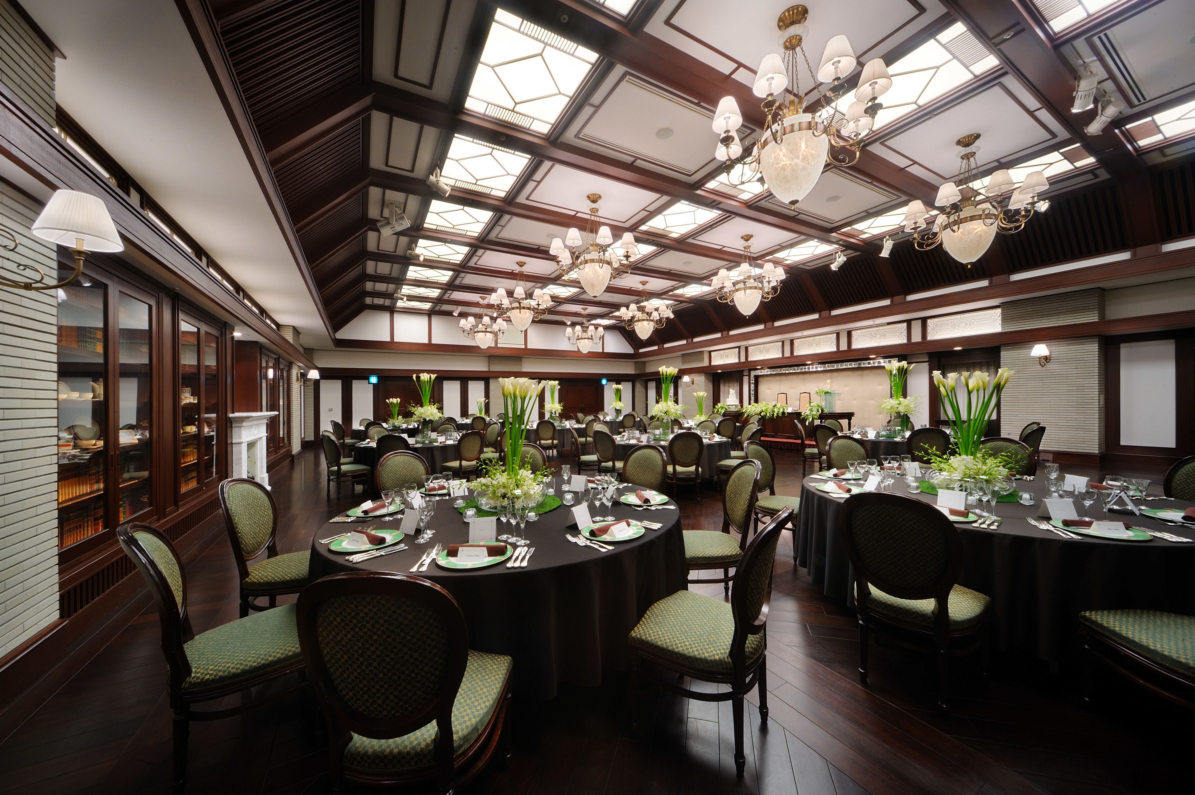 Un comedor elegante con mesas redondas, sillas y candelabros.