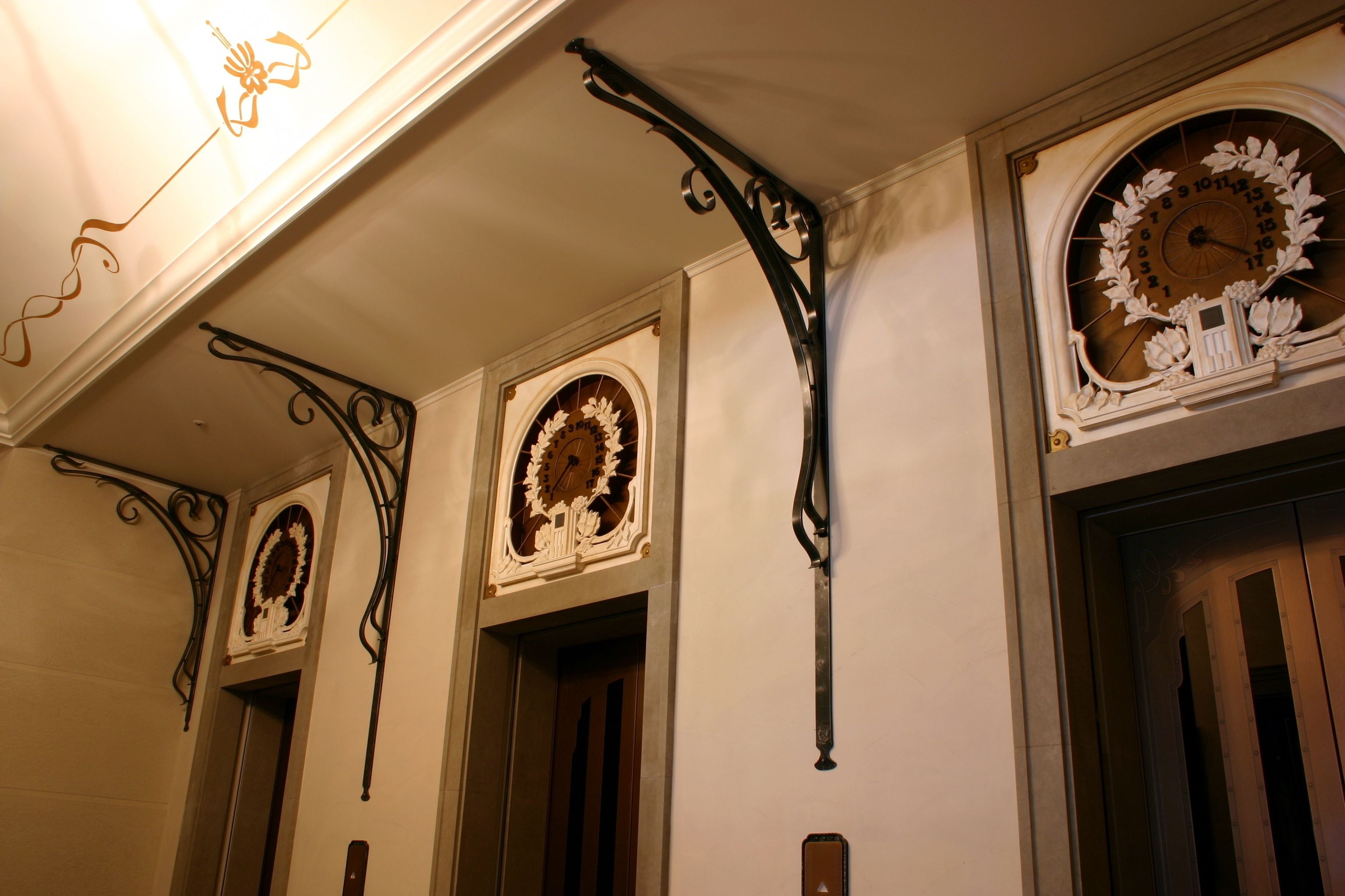 A hallway with ornate wall clocks and decorative metalwork.
