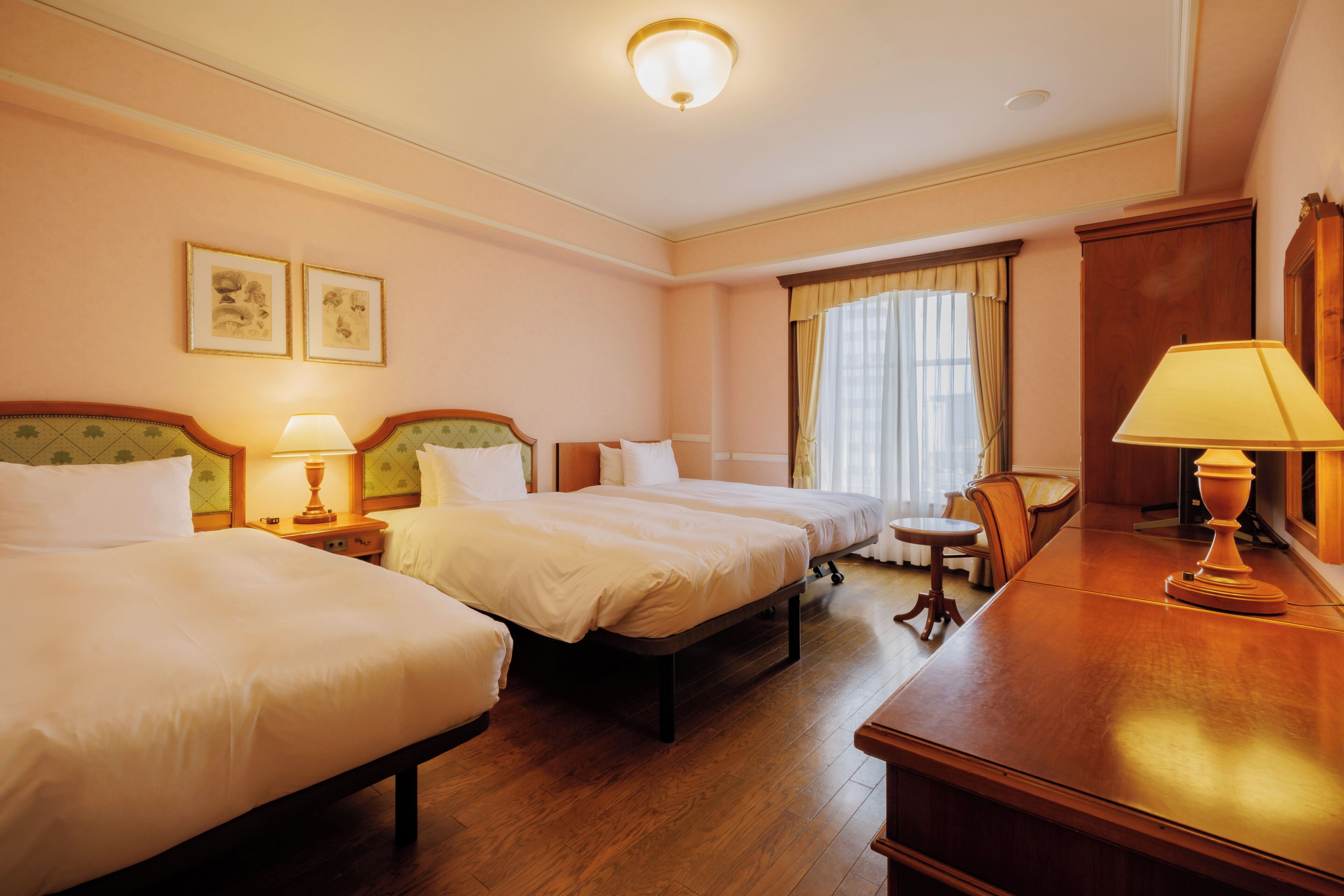Una habitación de hotel con dos camas, un escritorio, una silla y una mesita.