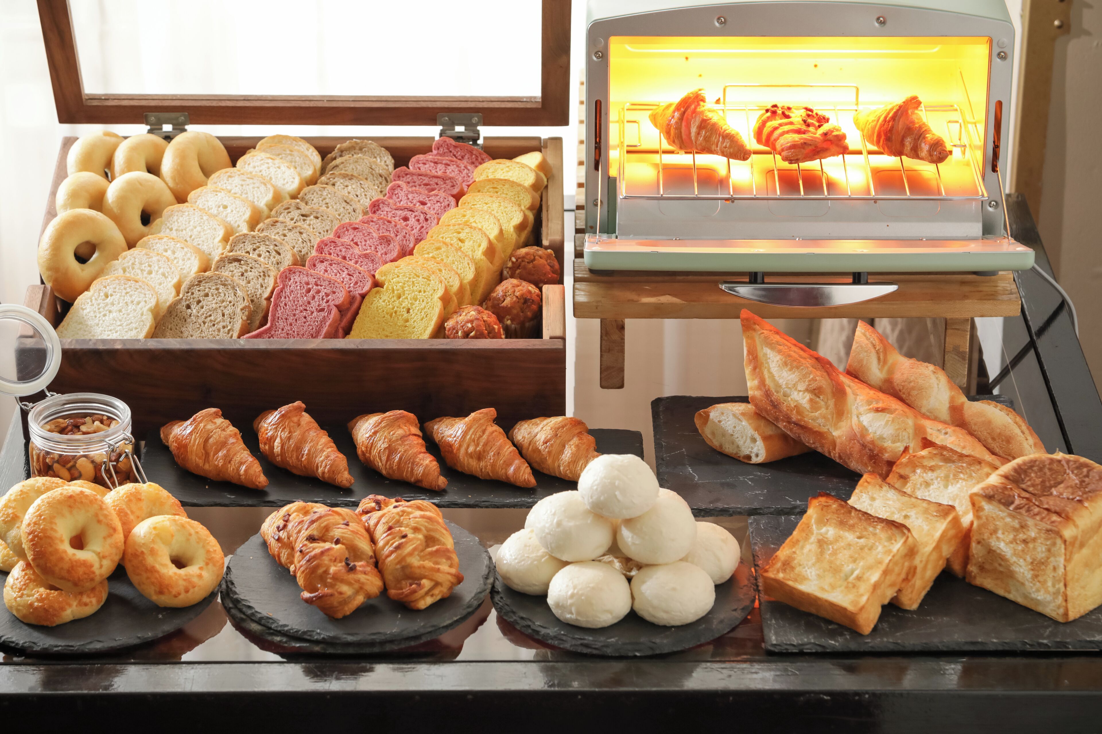 A variety of baked goods displayed in a bakery section, including bread, croissants, and pastries.