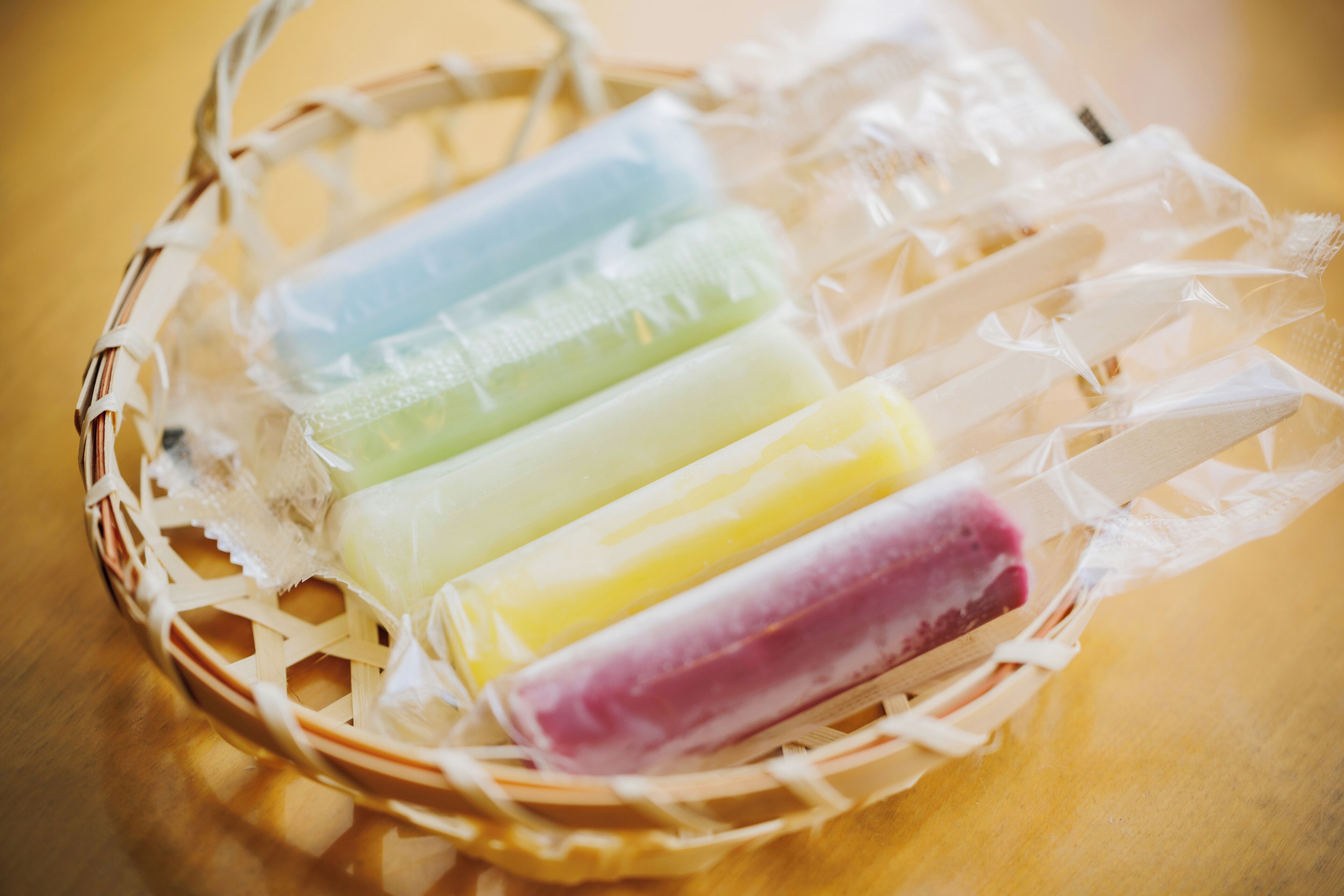 A basket containing several ice cream bars wrapped in plastic.