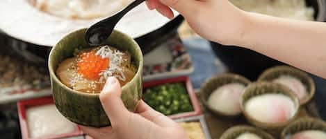 Una persona sosteniendo un cuenco con una cuchara, que contiene un plato de huevas de pescado naranja y arroz blanco.