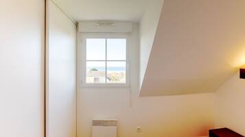 A bedroom with a window, a radiator, and a bedside table.