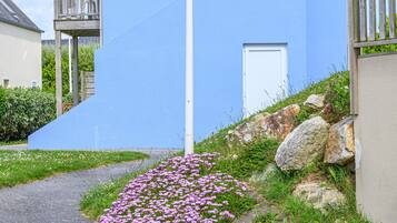 Ein Weg führt zu einem Gebäude mit blauer Fassade und einer weißen Tür.