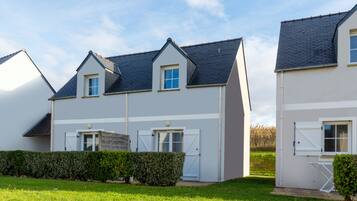 Een modern huis met twee verdiepingen, een grijze gevel en een donker dak, met een garage en een kleine zij-ingang.