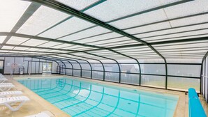 Una piscina interior con carriles delimitados, un puesto de socorrista y sillas de descanso a lo largo de la orilla.