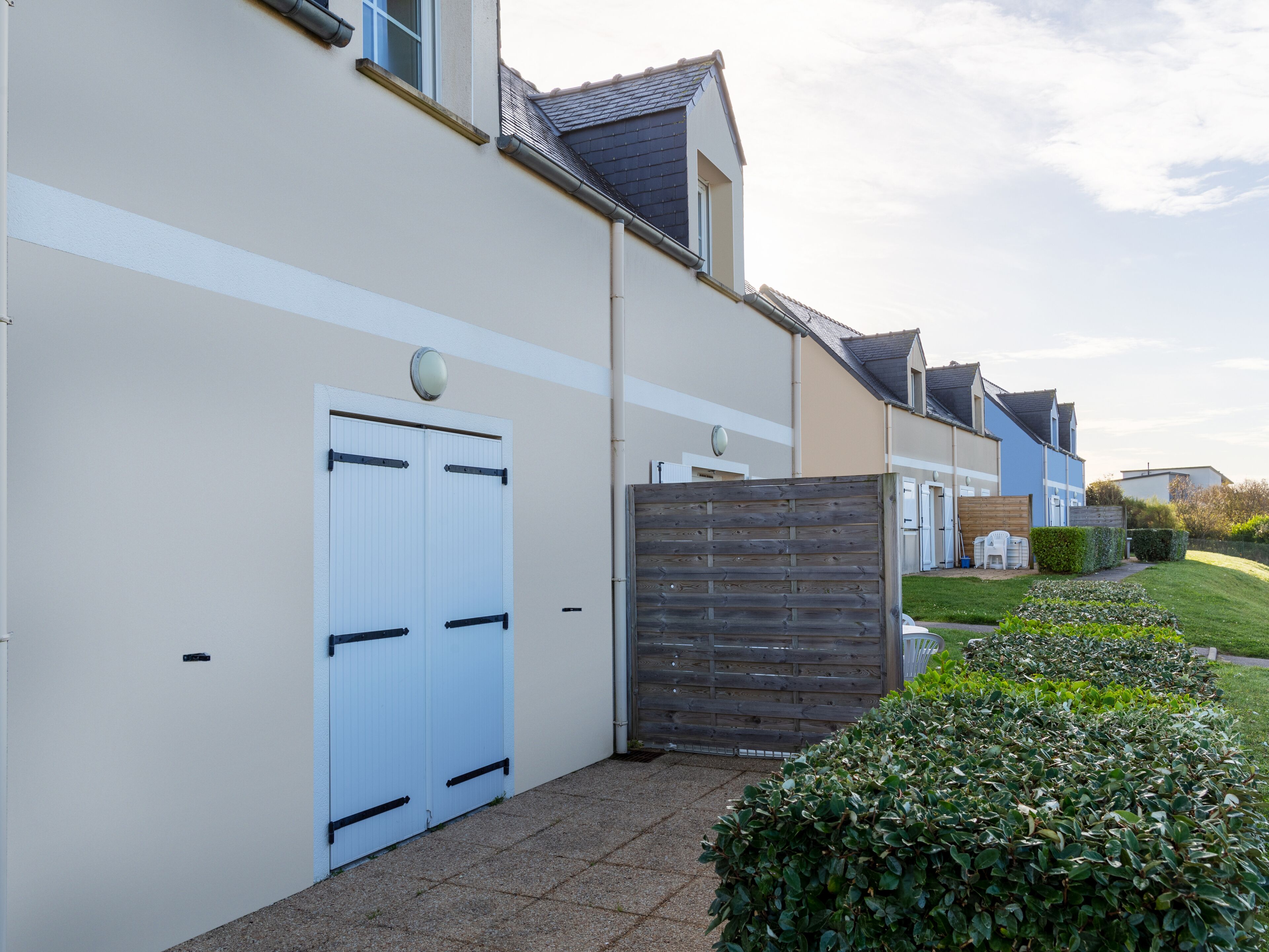 Une rangée de maisons résidentielles avec des portes blanches, une clôture en bois et un jardin bien entretenu.