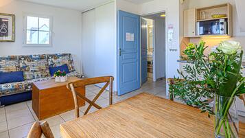 A cozy living room with a blue door, a dining table, and a sofa with a nautical theme.