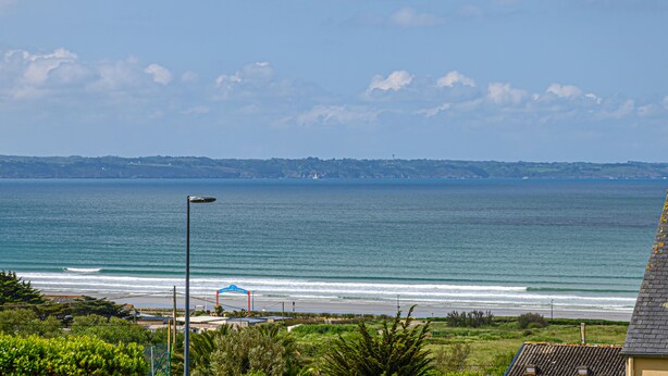 Vista costera con playa, océano y colinas distantes.