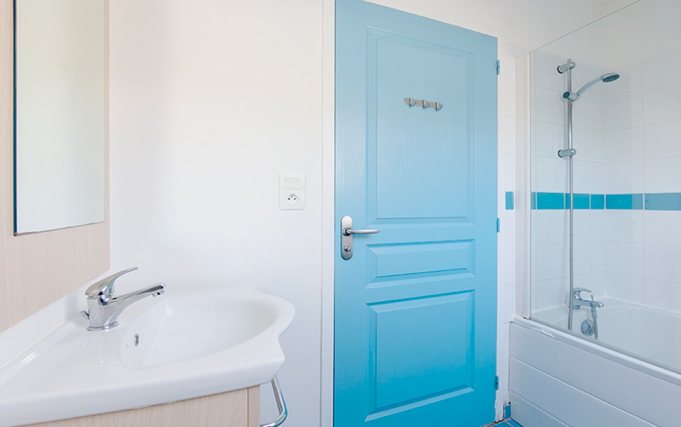 A bathroom with a white sink, a blue door, and a shower area.