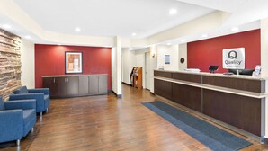 Ein Hotel-Empfangsbereich mit roter Wand, einer Rezeption und einer Sitzecke mit blauen Stühlen.