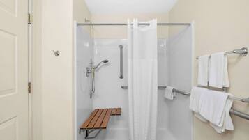 A shower area with a bench, a towel rack, and a shower curtain.