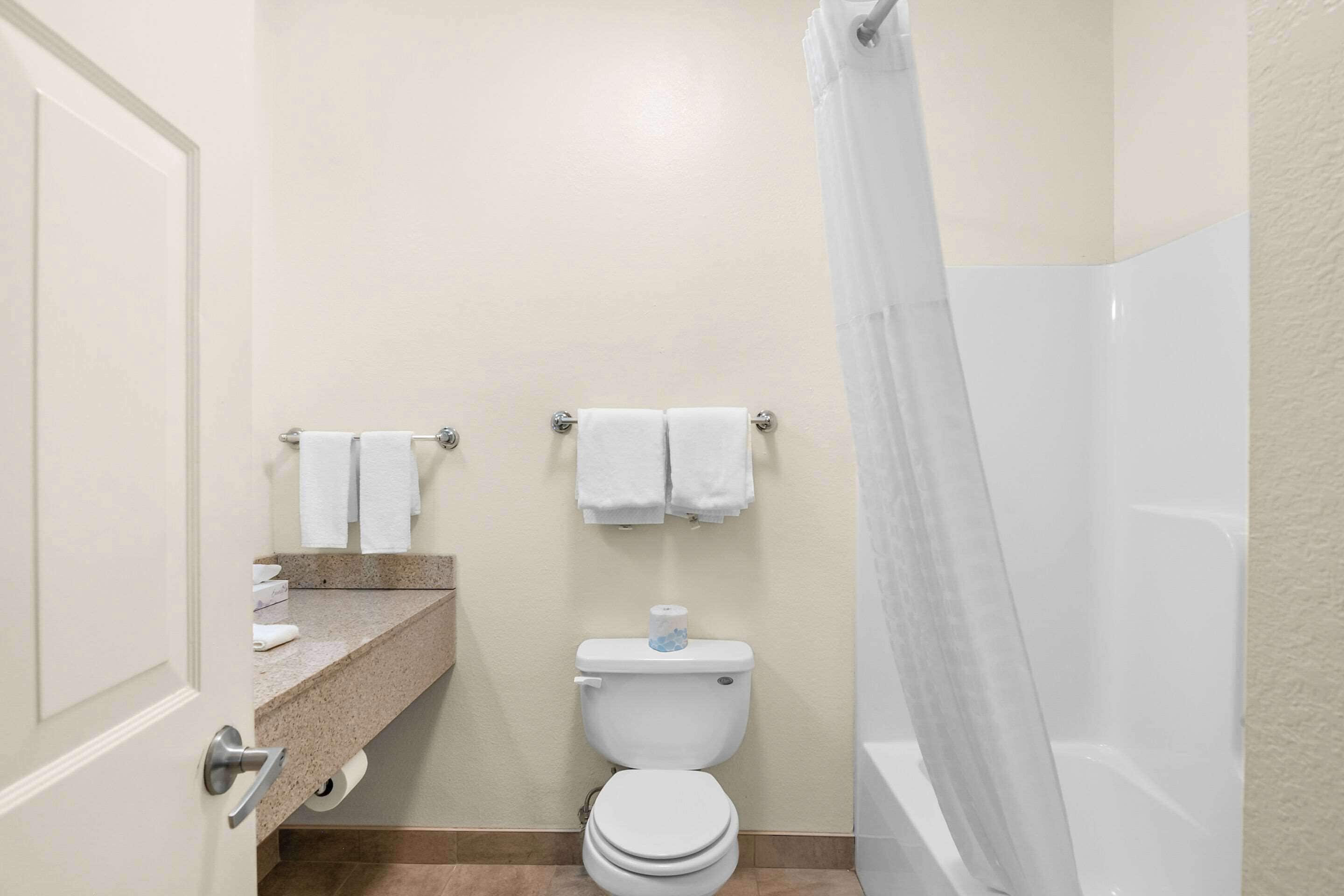 A bathroom with a toilet, a sink with a towel rack, and a shower area.