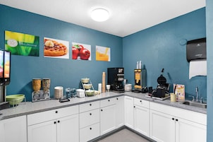 Una cocina con armarios blancos, una cafetera, un fabricante de gofres y un dispensador de café.