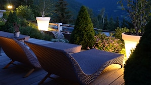 Une terrasse dotée de chaises longues et de plantes en pot, offrant une vue sur un paysage montagneux.