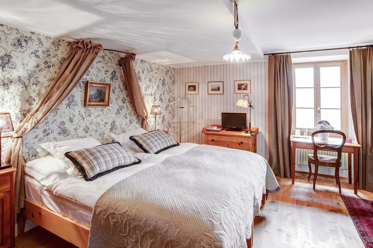 Un dormitorio con cama, escritorio, silla y televisor.