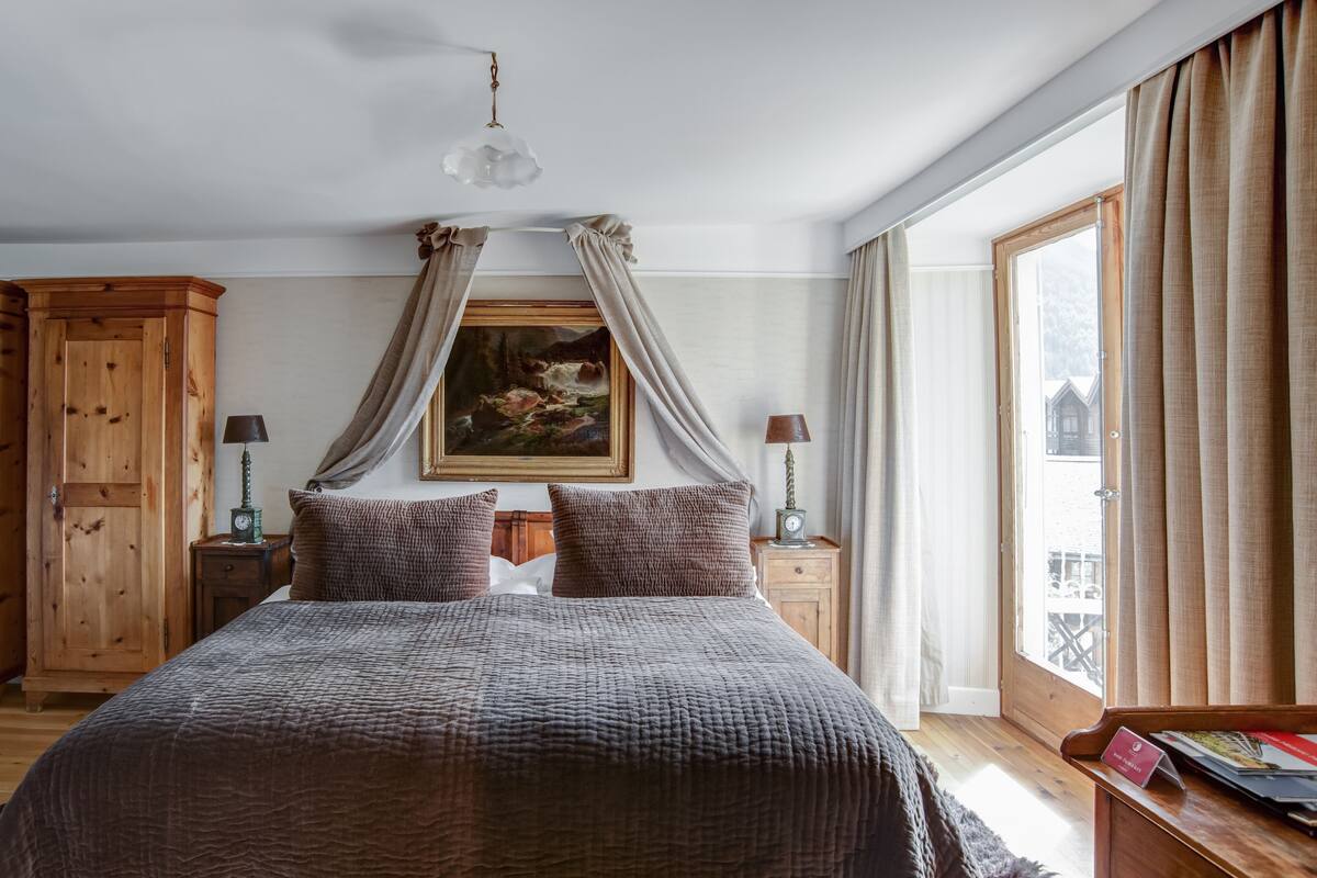 Un dormitorio con una cama grande, un armario de madera y un cuadro en la pared.