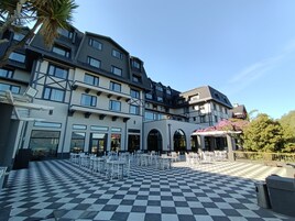 A hotel courtyard with a checkered floor, multiple balconies, and outdoor seating.