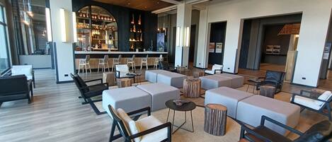 A spacious lobby with a bar area, seating arrangements, and a modern ceiling design.