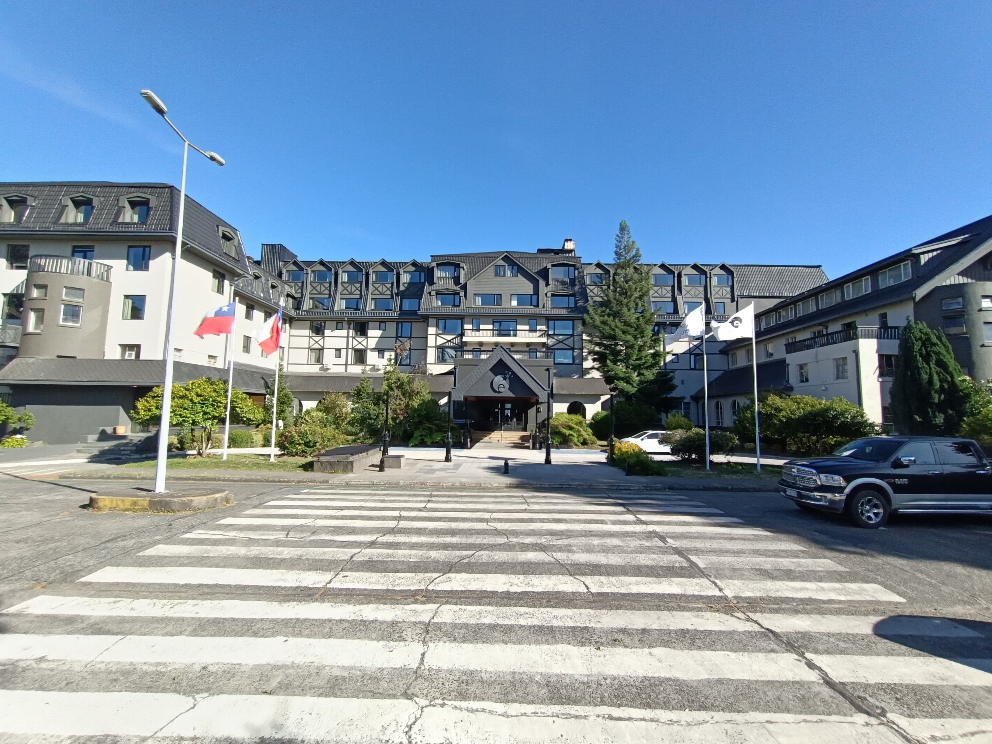 Un paso de peatones que lleva a un edificio con varios balcones y una bandera.