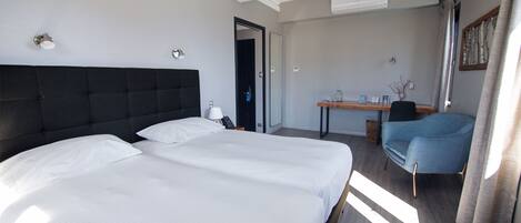 A hotel room with a large bed, a desk, and a chair.