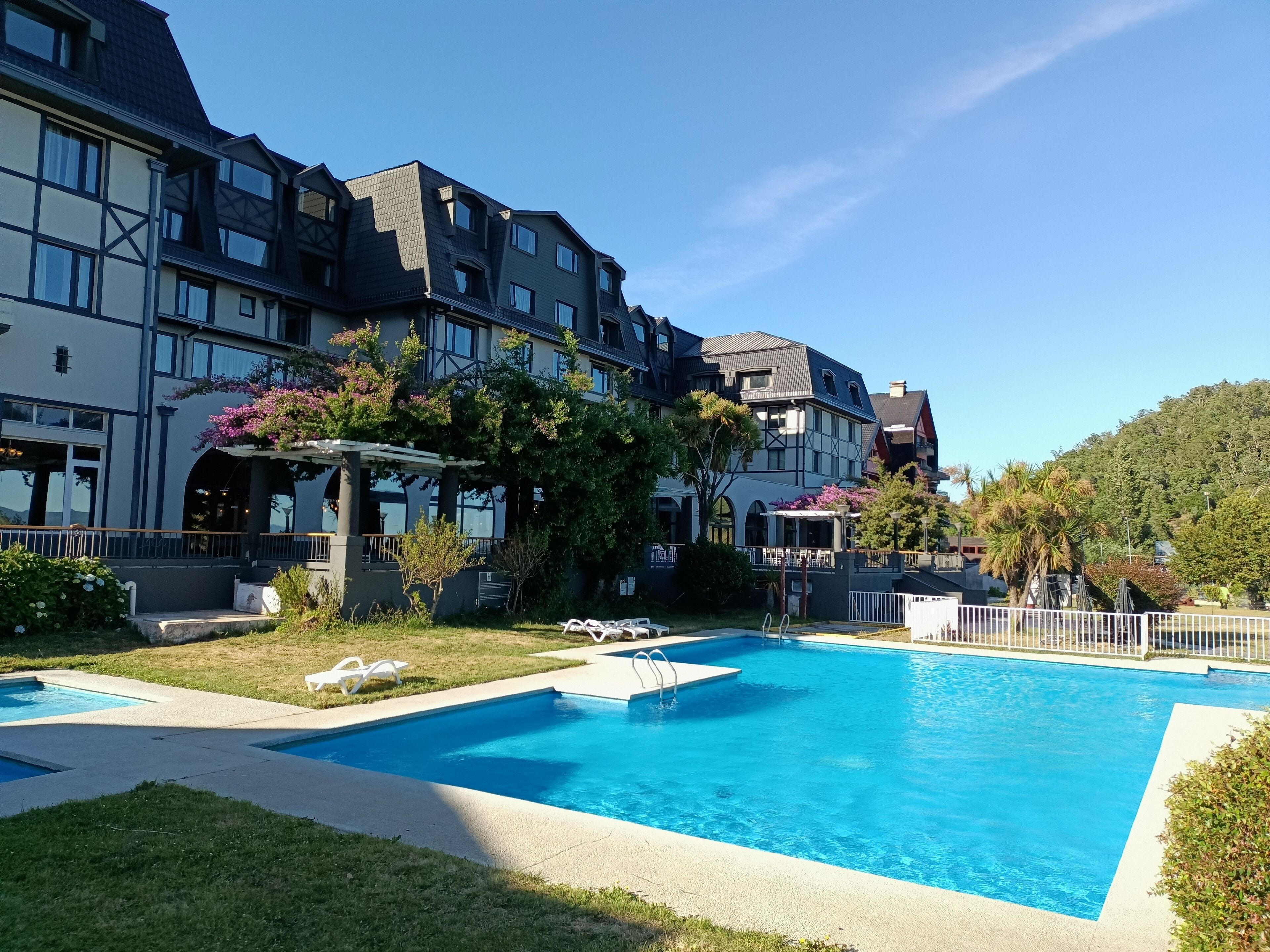A hotel with a swimming pool, outdoor seating, and a garden area.