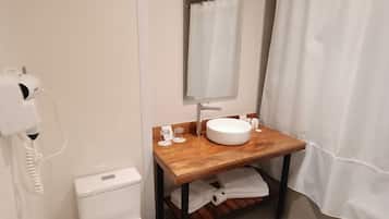 A bathroom with a toilet, a sink with a mirror, a shower curtain, and a towel rack.