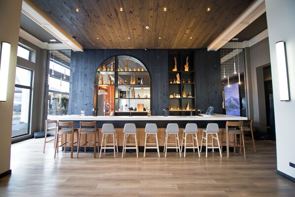A modern bar area with a wooden ceiling, a large central bar, and multiple seating options. - Enjoy Pucon (Pucón)