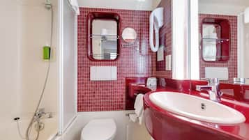 Une salle de bain avec des toilettes blanches, un lavabo rouge et un espace douche.