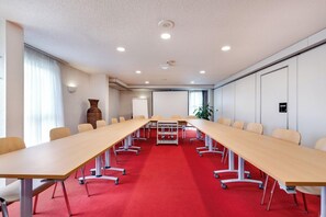 A conference room with a long table, chairs, and a red carpet. - Brit Hotel Confort Rouen Nord - Eden (Bois-Guillaume)