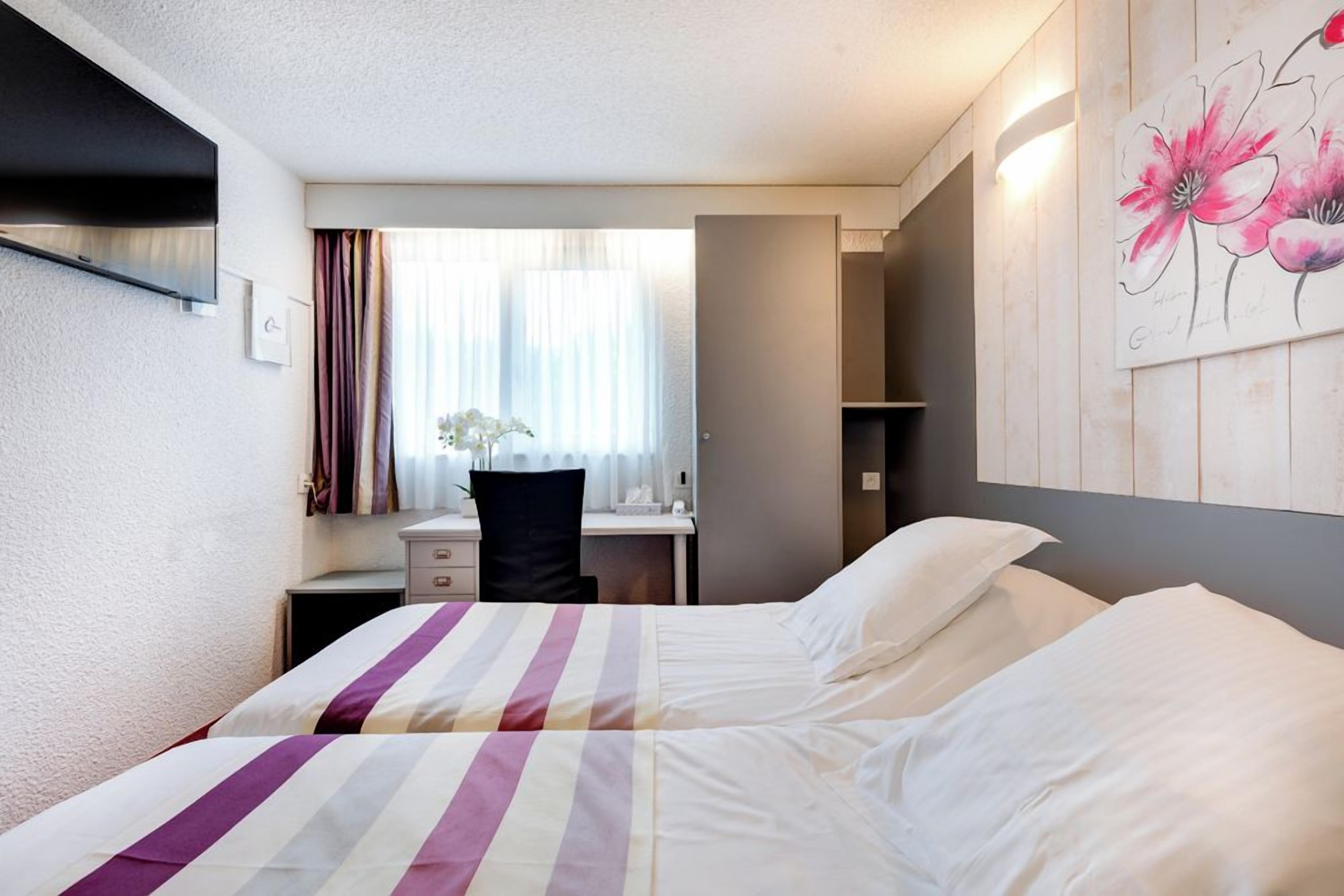 Ein Hotelzimmer mit zwei Betten, einem Schreibtisch und einem Stuhl.