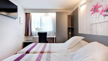 Ein Hotelzimmer mit zwei Betten, einem Schreibtisch und einem Stuhl.