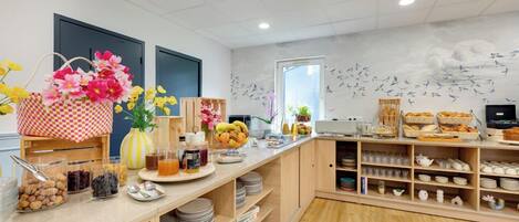 A breakfast buffet with various food items and a decorative wall mural.