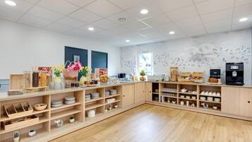 Una habitación amplia con suelo de madera, una encimera larga con varios objetos y un mural de aves en la pared.