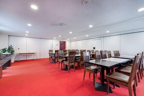 A conference room with multiple tables and chairs, a red carpet floor, and white walls. - Brit Hotel Confort Rouen Nord - Eden (Bois-Guillaume)