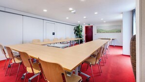 Una sala de conferencias con una larga mesa, sillas y una alfombra roja.