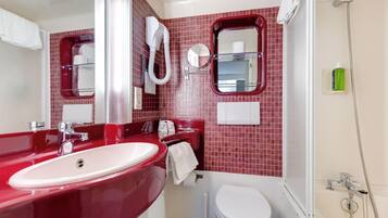 Une salle de bain avec un lavabo rouge, des toilettes blanches et un espace douche.
