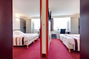 A hotel room with two beds, a desk, and a mirror.