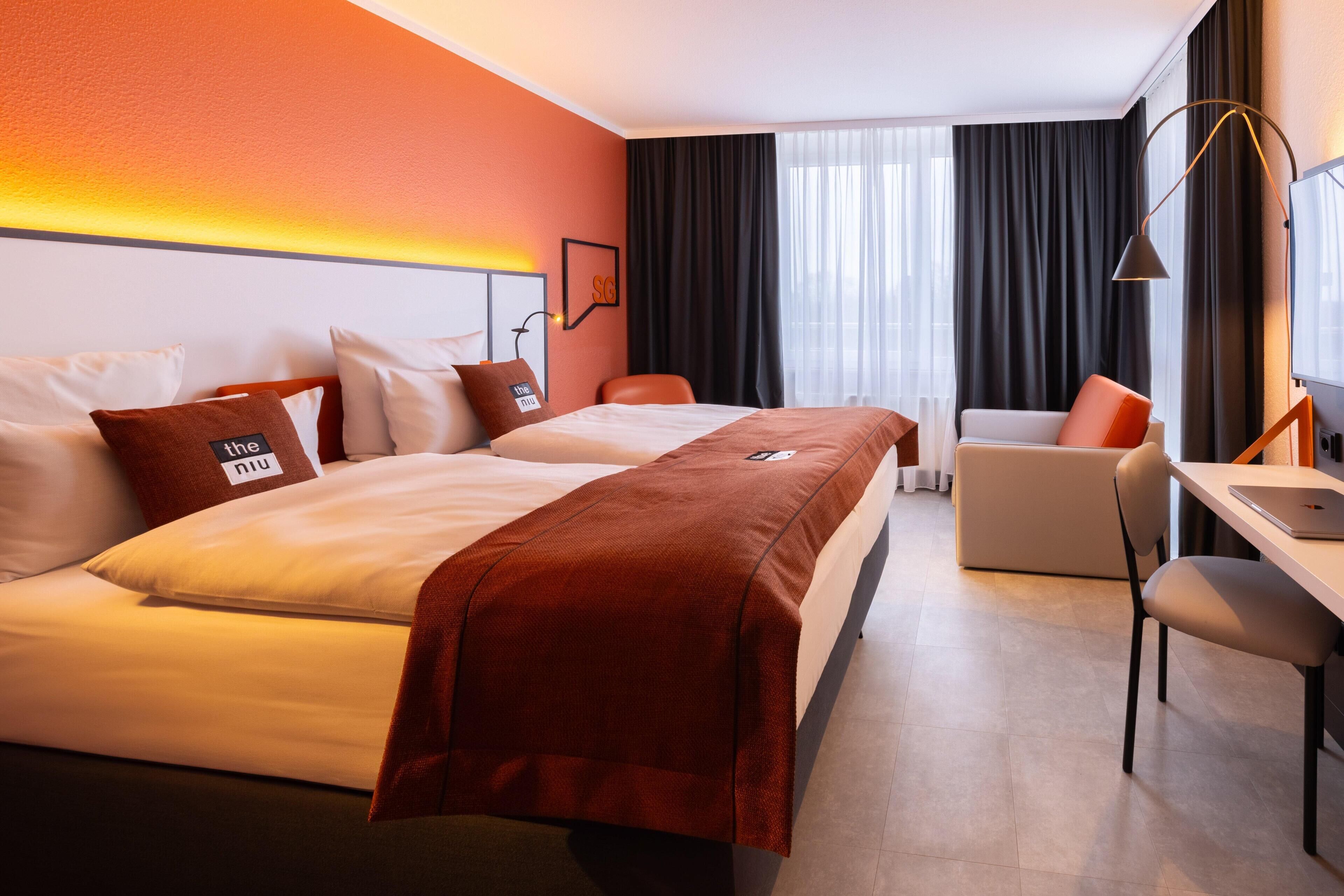 A hotel room with a bed, a desk, a chair, and a TV.