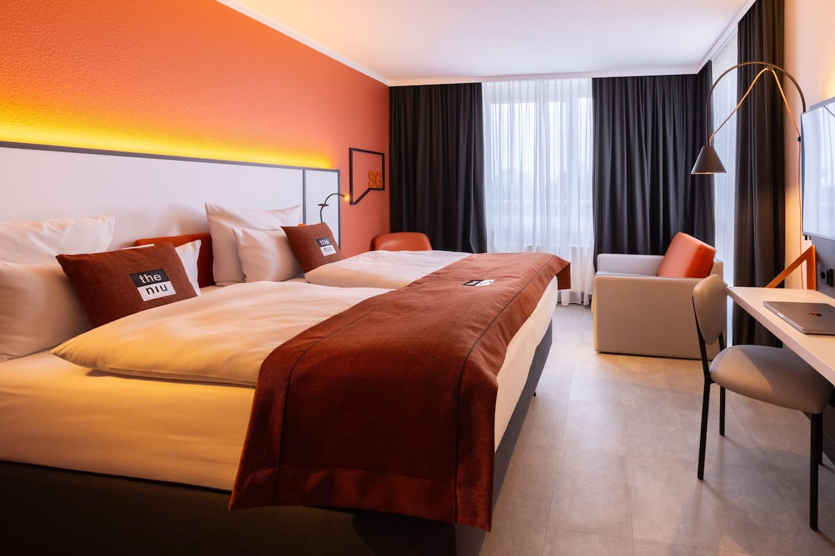 Una habitación de hotel con cama, escritorio, silla y televisor.