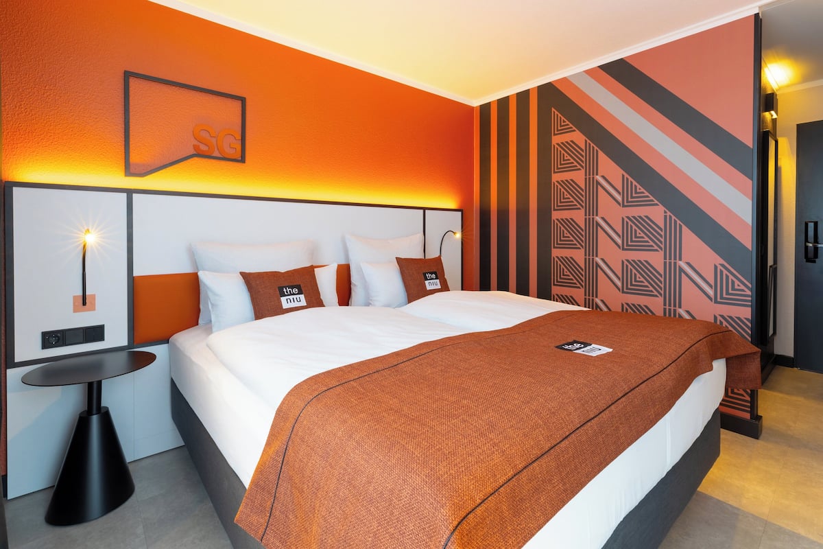 Ein Hotelzimmer mit einem großen Bett, einem Nachttisch und einer Wand mit geometrischem Muster.
