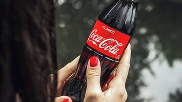 Une personne tenant une bouteille de Coca-Cola.