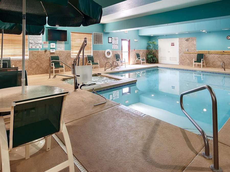 Una piscina techada, sombrillas, sillones reclinables de piscina