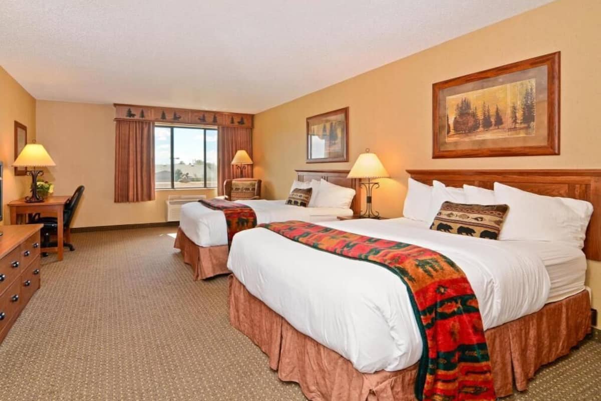A hotel room with two beds, a desk, and a chair.