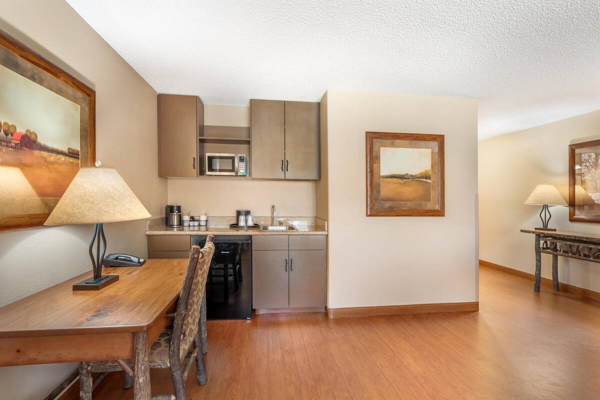 A compact kitchen with a microwave, cabinets, and a dining area with a wooden table and chairs.