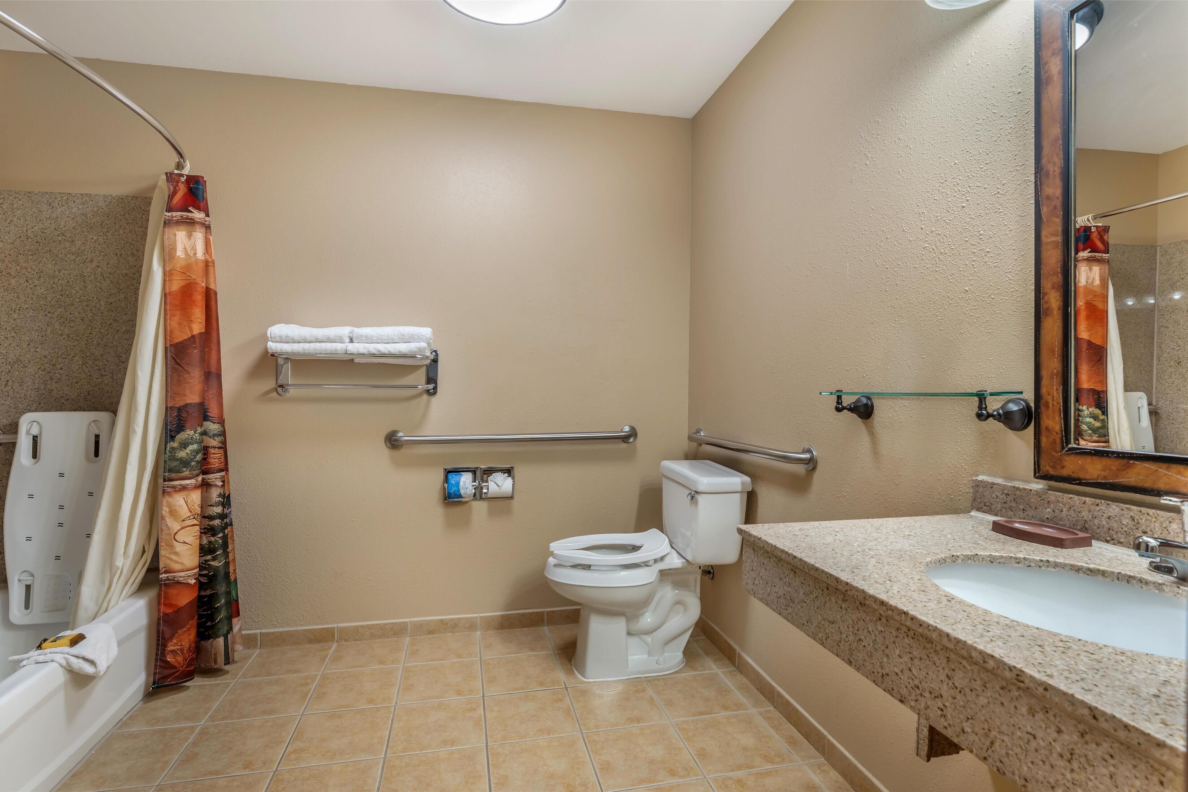 A bathroom with a toilet, sink, shower, and grab bars.