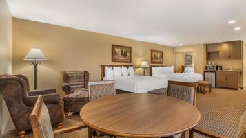 A hotel room with a bed, two bedside tables, a desk, a chair, a round table, and a lamp.